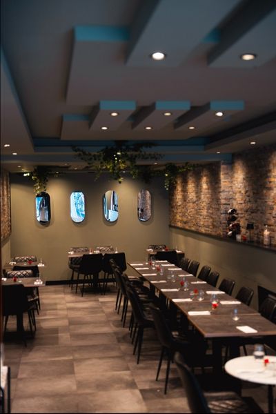 Long set dining table and seating with exposed stone wall and soft lighting at Mangia Pizza